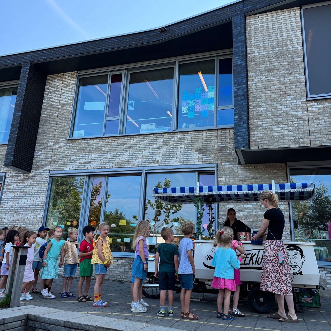 Kinderen in rij bij ijskar voor schoolgebouw